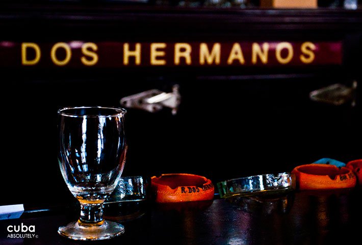 glass with the sign of Dos Hermanos restaurant behind© Cuba Absolutely, 2014