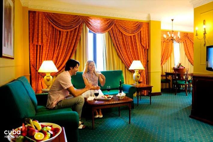 Parque Central hotel in Old Havana, couple at a yellow room with green couchs and orange curtain © Cuba Absolutely, 2014 - 2020