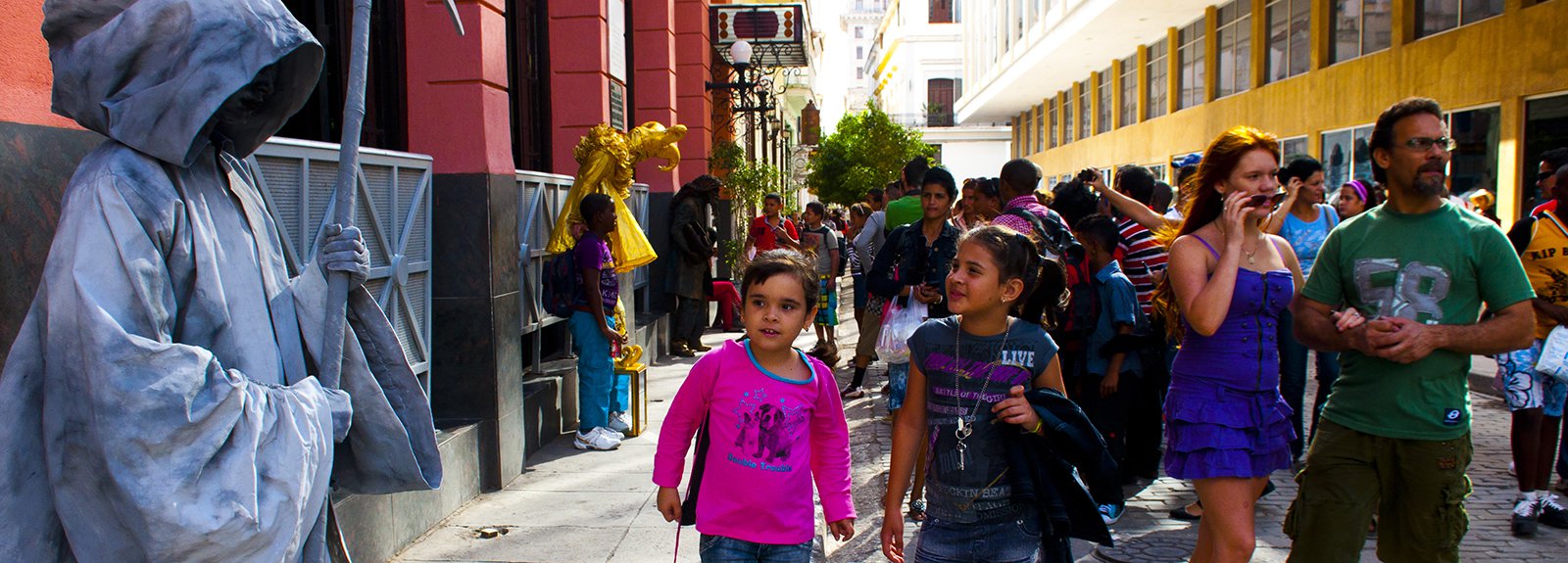 Living statue in gray on the left, child with a pink blouse on the right