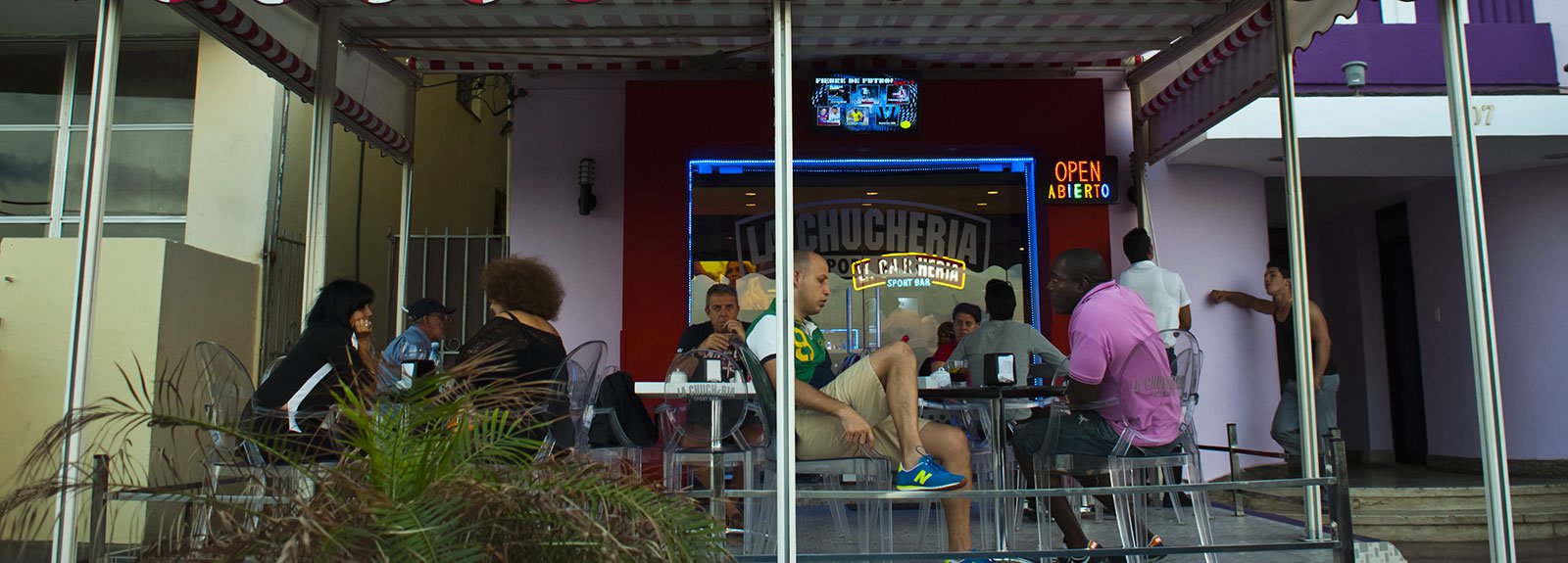 eople eating and drinking at Chucheria restaurant outdoors terrace in Vedado, transparent table and chairs