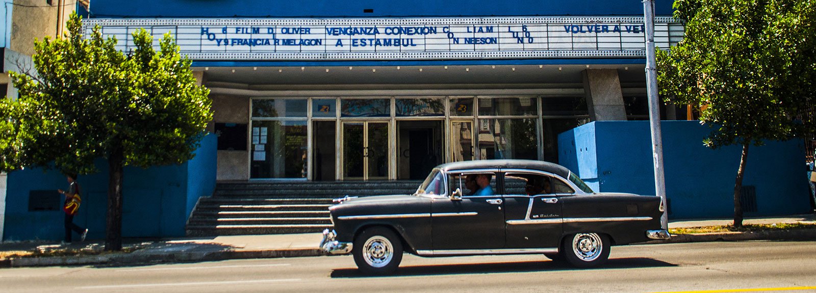 Riviera cinema, black old car passing by the street