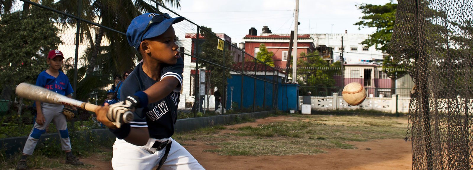 Kid playing baseball with a white and blue uniform