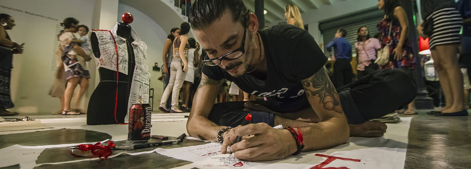 Man writing on a paper in the floor on a exhibition at factoria habana gallery