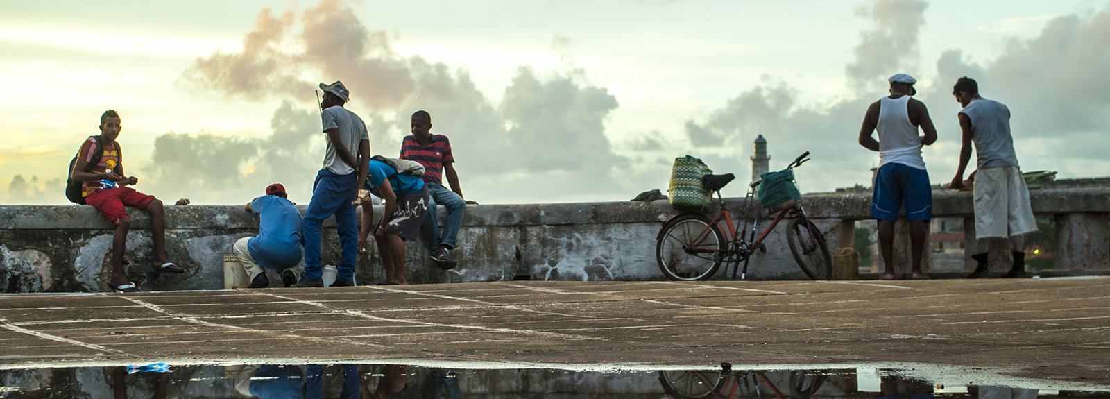 Seawall, people fishing reflect on the water on the sidewalk